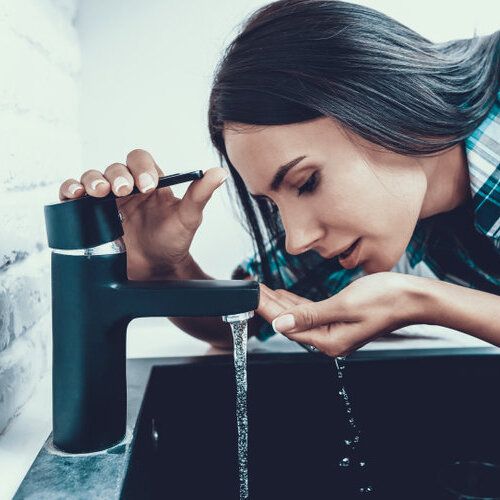 woman drinking water from the tap